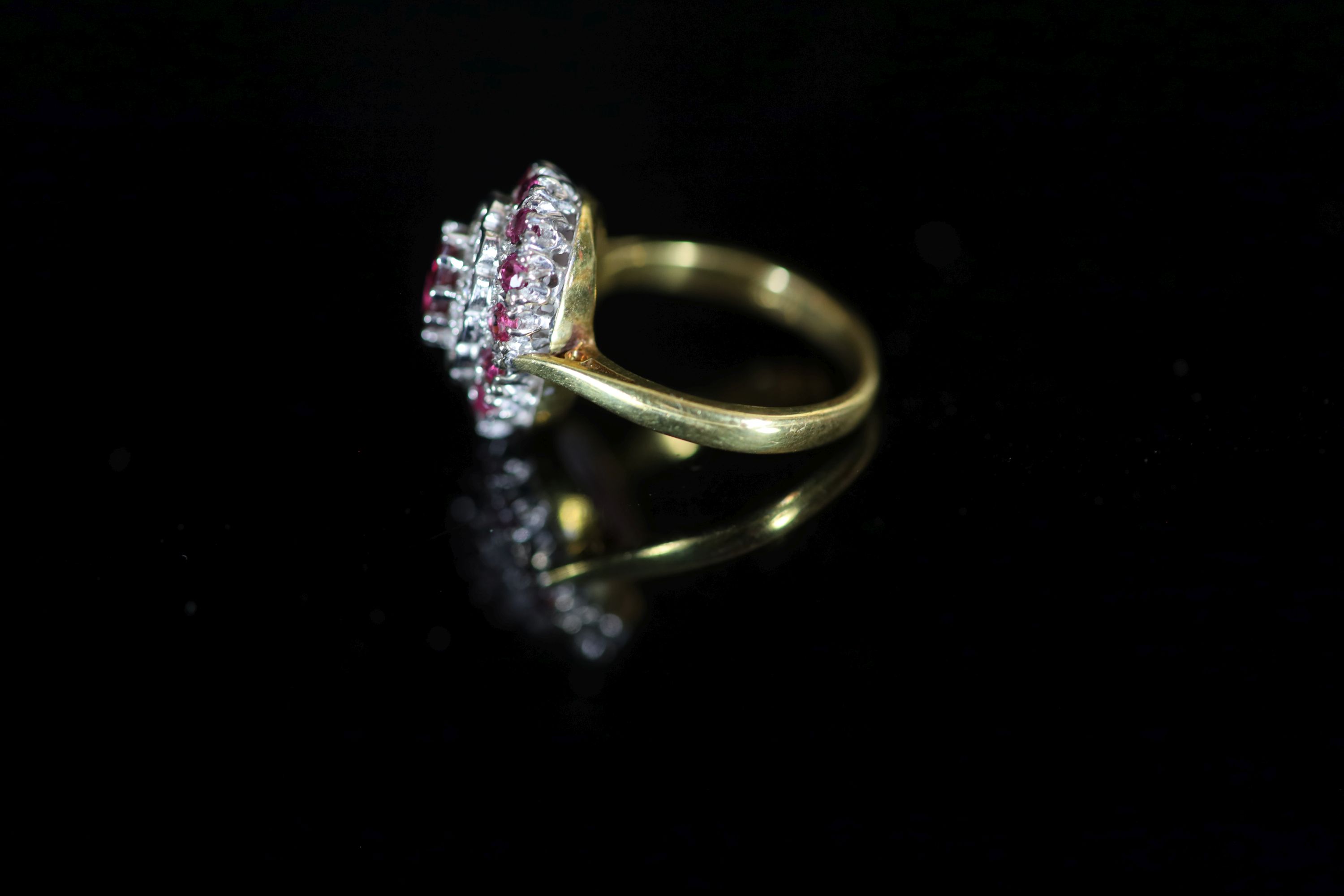 A modern 18ct gold, ruby and diamond set oval cluster ring